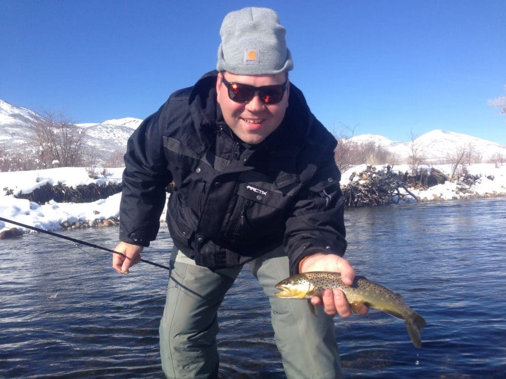 Proud man holding brown trout during while winter fishing 