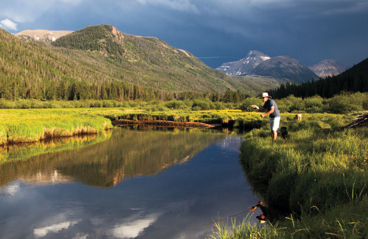 Person fishing the Uinta River with mountains in the background
